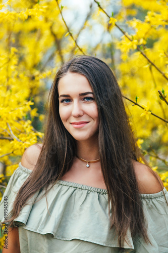 Happy smiling young woman with spring flowers at garden