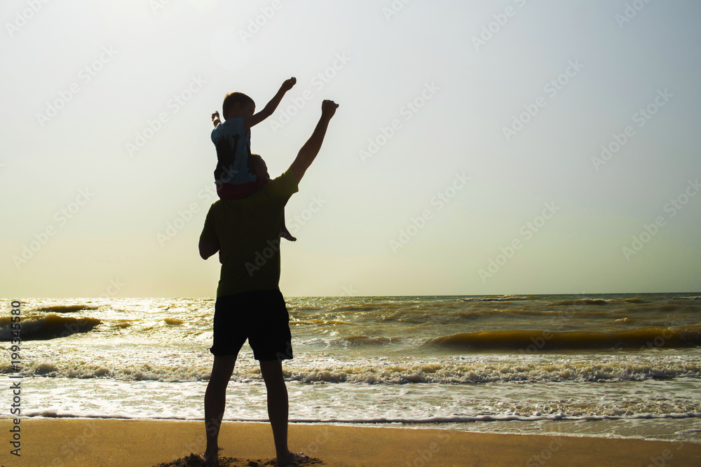 Fototapeta premium Father and son playing on the beach at the sunset time. Concept of friendly family