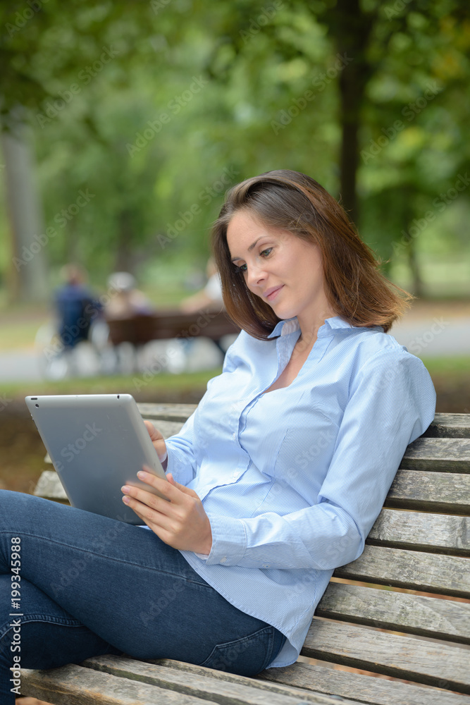 Lady on park bench looking at tablet Lady on park bench looking at tablet