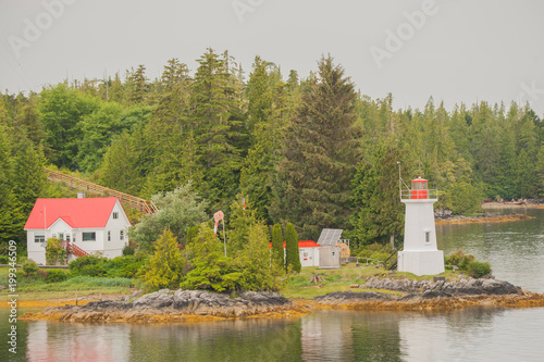 Canadas Westen, kleine Insel mit Leuchtturm und Haus im Vordergrund in der Inside Passage, bewaldete Hügellandschaft.