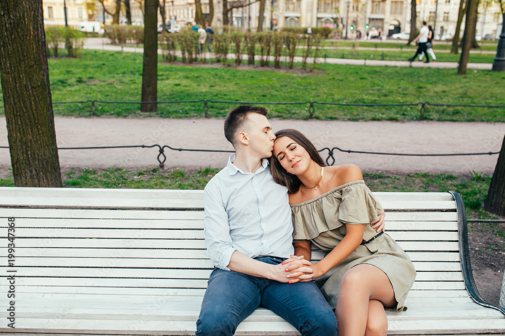 Happy young couple in love sitting on a park bench and hugging Happy young couple in love sitting on a park bench and hugging