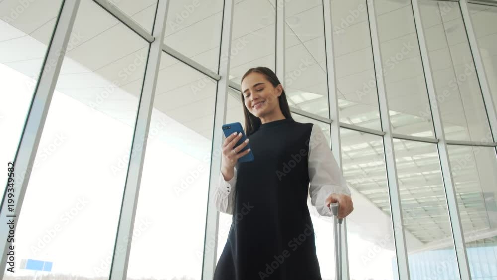 Tourist woman in international airport terminal with luggage using smart phone. Voice recognition text message command helper