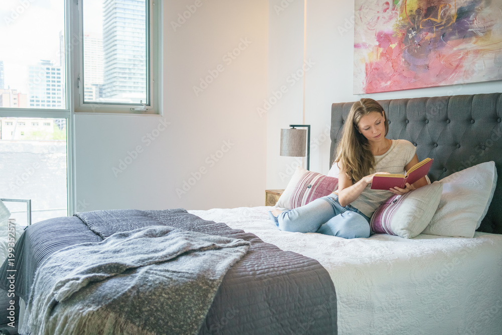 Relaxed young woman reading book in bed at home Relaxed young woman reading book in bed at home