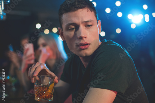 Portrait of weary bibacious man drinking glass of whiskey. He resting in bar. Fatigue and leisure concept photo