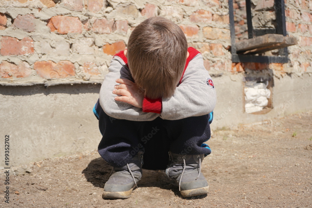 Fototapeta premium A Sad and lonely boy beside brick wall