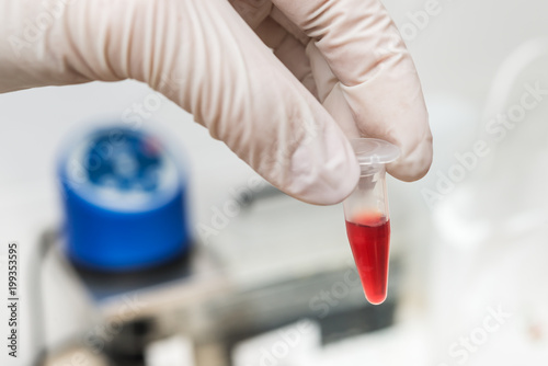 Scientist or technician holding a tube with blood sample