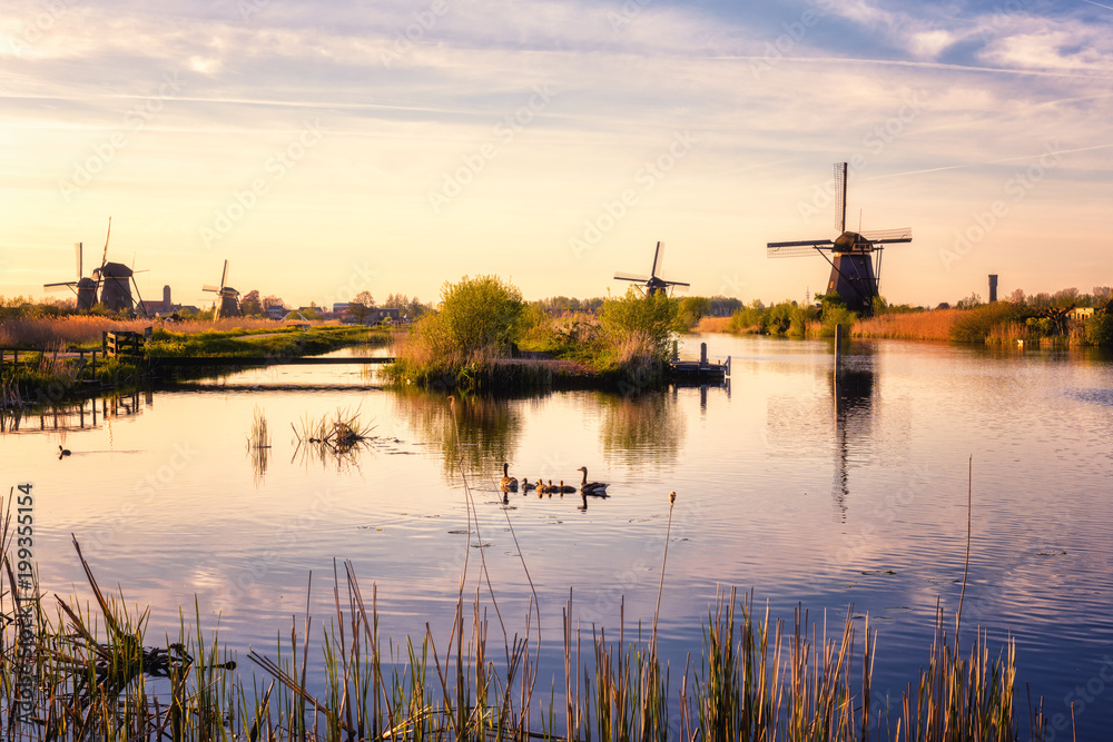 Scenic sunset landscape with windmill, blue sky and reflection in the water. Traditional dutch countryside, famous village of mills Kinderdijk, Netherlands (Holland)