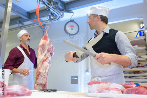 two butcher slicing ham and smiling in store