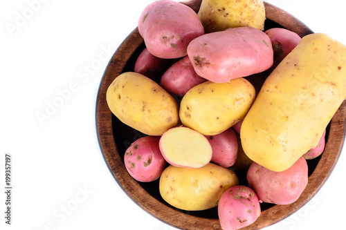 Raw mini potatoes in wooden bowl. Isolated macro food photo close up from above on white background.