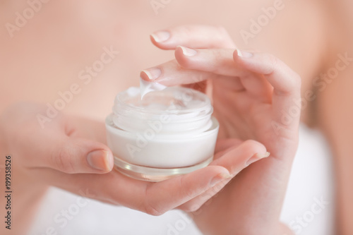 Young woman with jar of hand cream, closeup