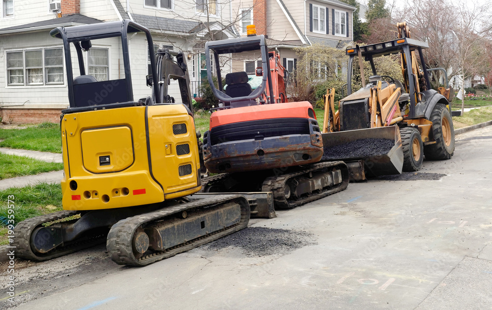 Heavy construction machinery parked on residential neighborhood street.