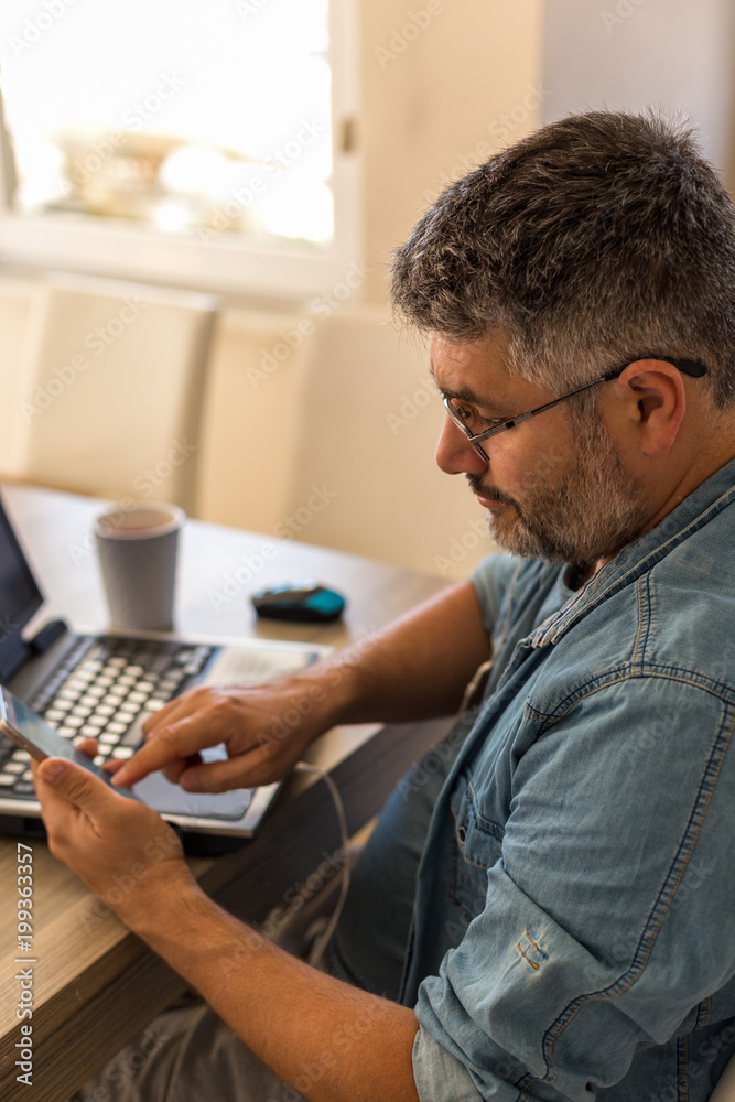 Obraz premium Man working using mobile phone and laptop