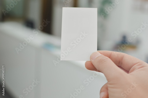Close up on hand of a businessman showing business card office space background