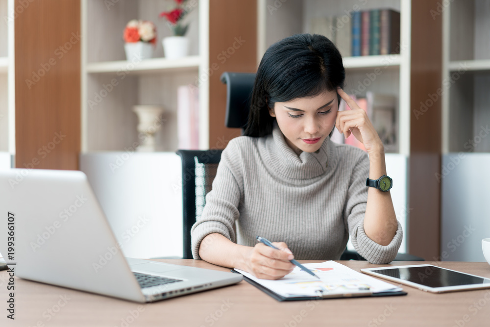 Portrait of a beautiful Asian young businesswoman sitting in the office, holding document and thinking. Portrait of a beautiful Asian young businesswoman sitting in the office, holding document and thinking.