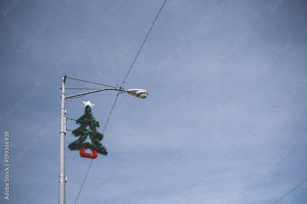 Low angle view of Christmas tree hanging on street light against sky Low angle view of Christmas tree hanging on street light against sky