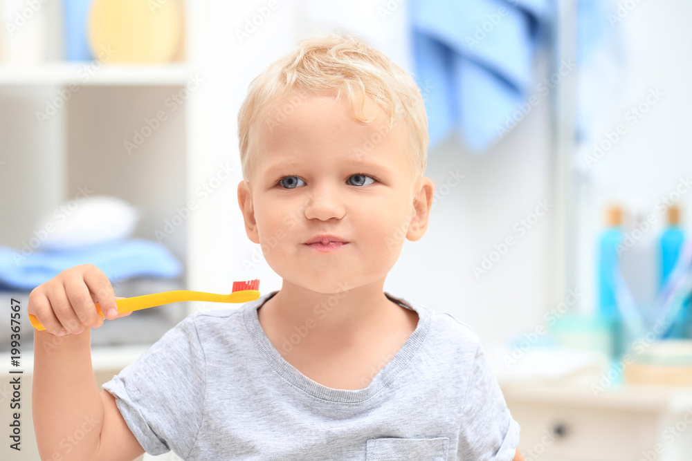 Cute little child cleaning teeth in bathroom