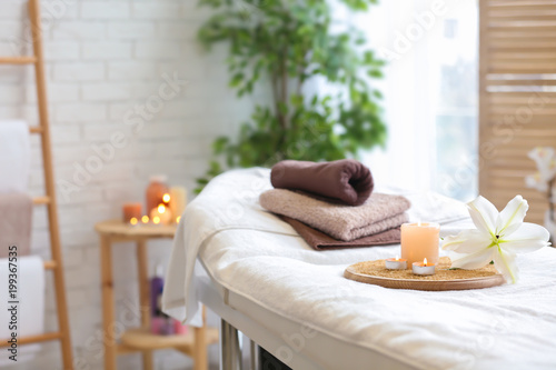 Ręczniki, świeczki i kwiat na stole do masażu w salonie spa