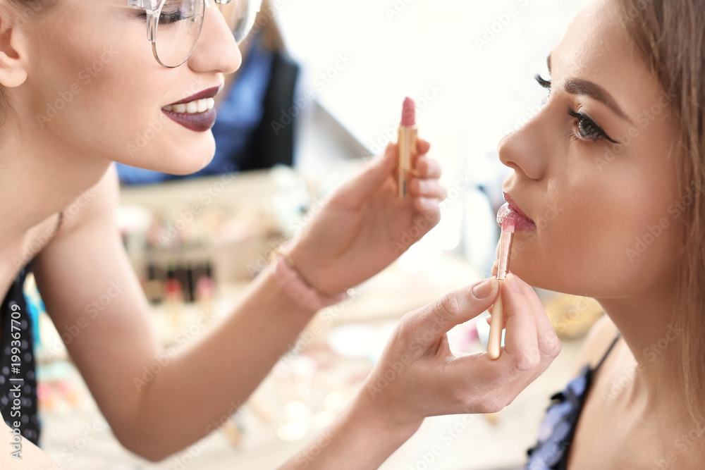 Professional makeup artist working with beautiful young woman in studio Professional makeup artist working with beautiful young woman in studio