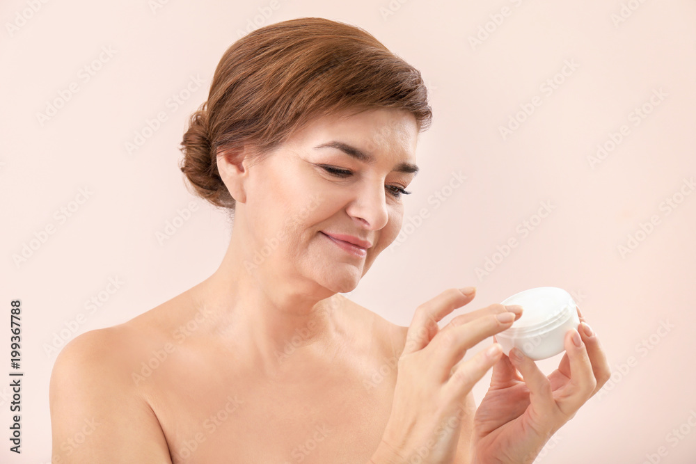 Portrait of beautiful mature woman with jar of anti-aging cream on light color background. Skin care concept Portrait of beautiful mature woman with jar of anti-aging cream on light color background. Skin care concept