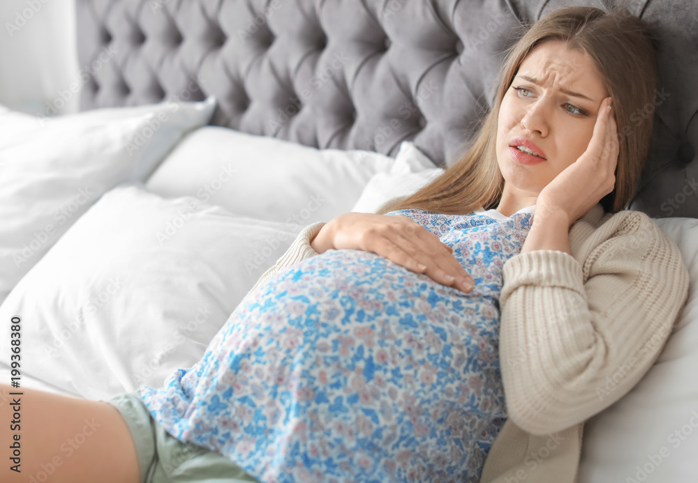 Young pregnant woman suffering from headache at home