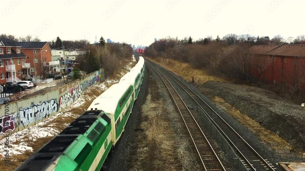 Overpass view looking down onto Go Train crossing under bridge, against skyline, on an overcast day