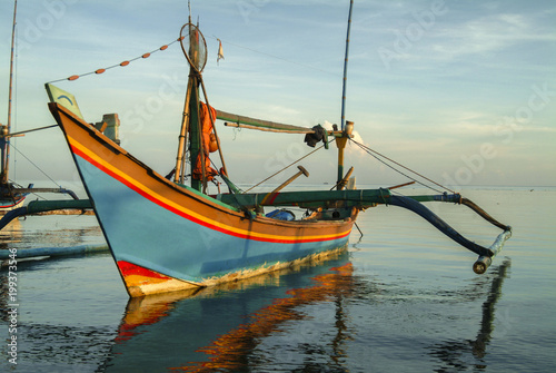 Balinese Fishing Boats Anchored in the Village of Pemuteran. Balinese fishing boats, called jukung, in the bay of northwest Bali, Indonesia during a beautiful sunrise.  photo