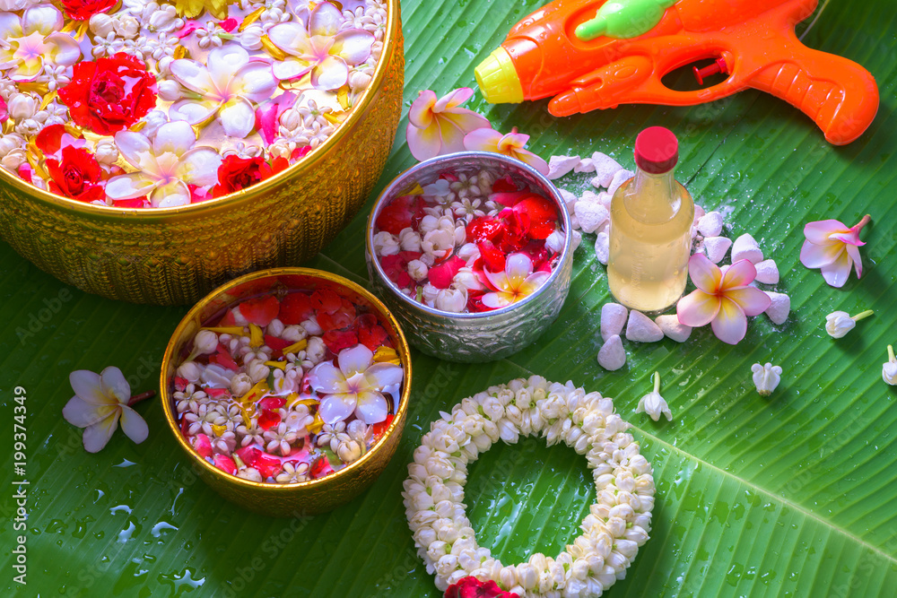 Thai traditional jasmine garland and Colorful flower in water bowls decorating and scented water, perfume, marly limestone, pipe gun on Banana leaf for Songkran Festival or Thai New Year