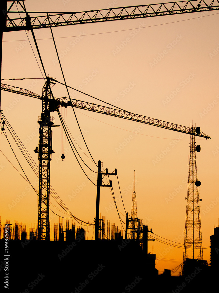 Fototapeta silhouette of building under construction with crane at sunset