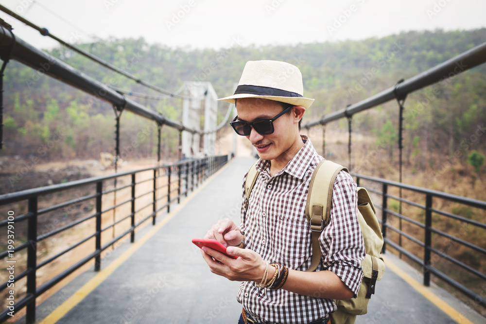 Young man traveller using mobile phone on bridge.
