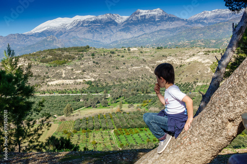 Boy watching farming landscape, Greece