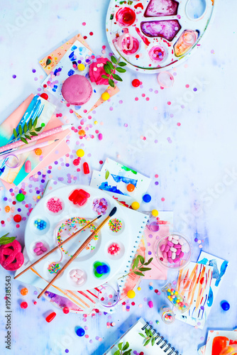 Colorful party activity concept with artist tools, brushes and palette full of sweets, sprinkles and candies. Creative celebration flat lay with copy space.