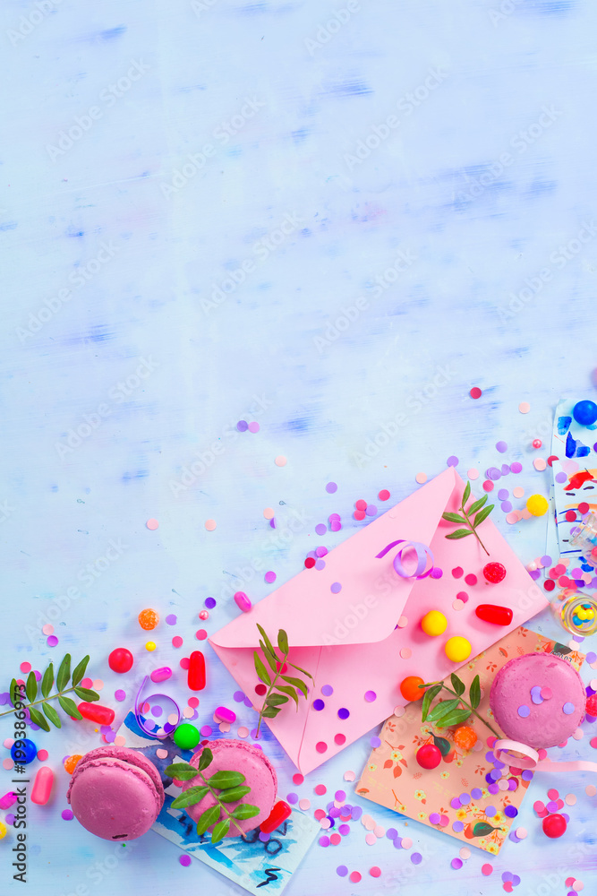 Love letter in a pink envelop with macarons, candies and confetti on a light background with copy space. Party invitation concept.
