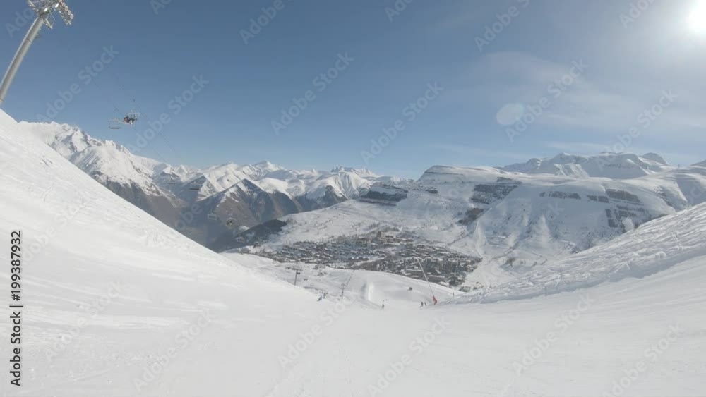 Skier quickly go down on ski route in sunny weather against mountain slopes Skier quickly go down on ski route in sunny weather against mountain slopes