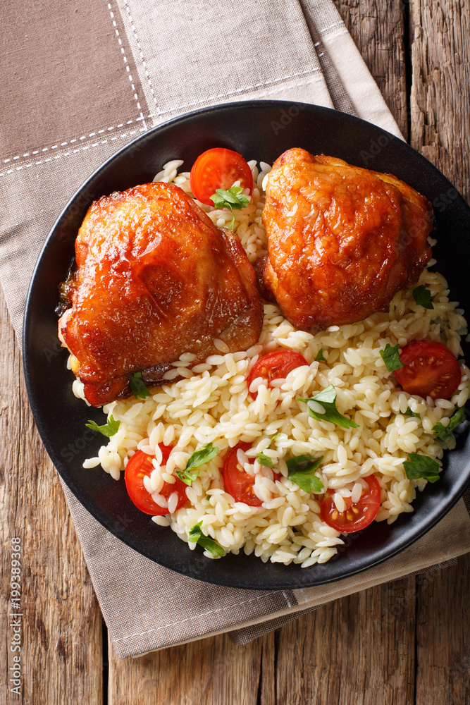 Portion of fried chicken thighs with garnish of rice with vegetables close-up. Vertical top view from above Portion of fried chicken thighs with garnish of rice with vegetables close-up. Vertical top view from above