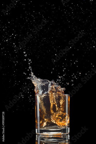 Glass of whiskey with splash isolated on black background © Vladyslav Bashutskyy