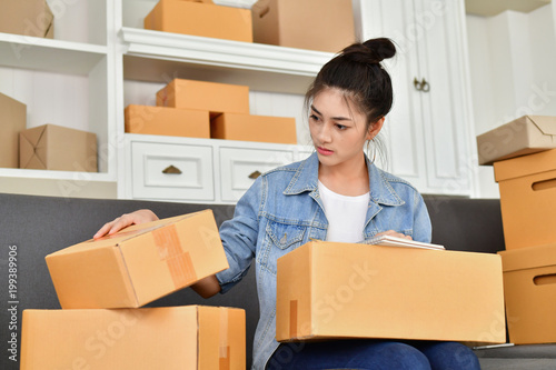 Sme business concept. Young Asian people are packing their packages.Delivery business Small and Medium Enterprise (SMEs). Young man is working in the house.Young Owner Start up for Business Online.