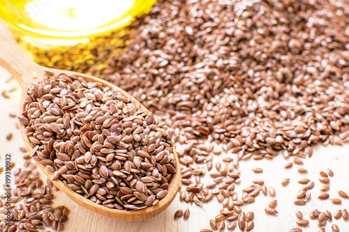 flax seeds in a wooden spoon, next flaxseed oil, on an old board