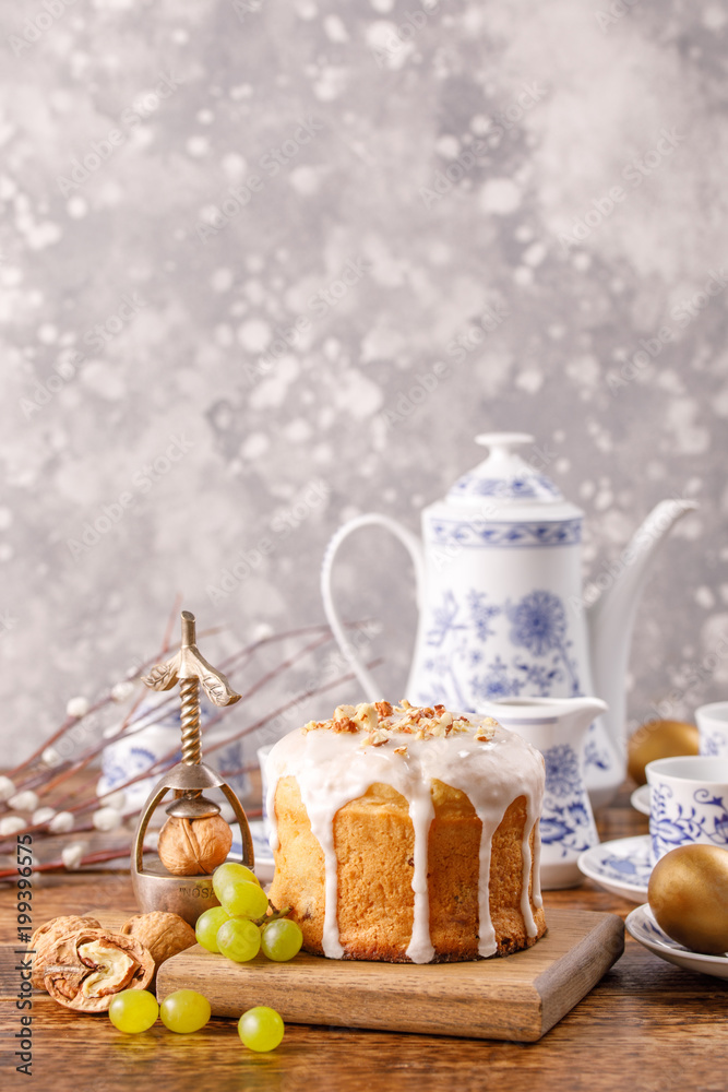 The table is set for Easter tea drinking. Delicious homemade Easter cake and golden eggs. Postcard with a place under your text.