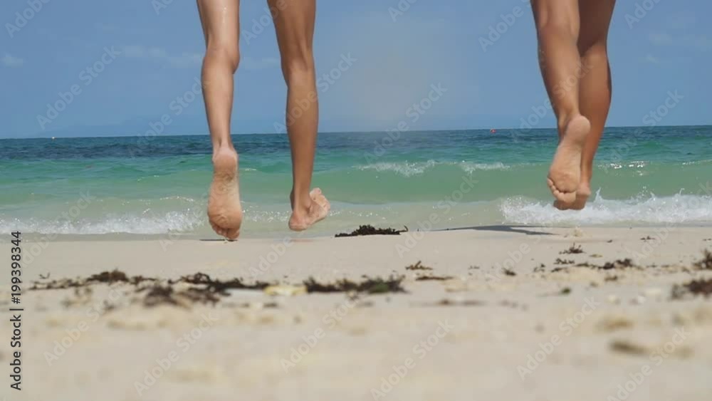 Young happy couple running at the beach to the sea and holding hands of each other. Girl and boy having fun together at summer vacation or holiday. Slow motion. 1920x1080 Young happy couple running at the beach to the sea and holding hands of each other. Girl and boy having fun together at summer vacation or holiday. Slow motion. 1920x1080