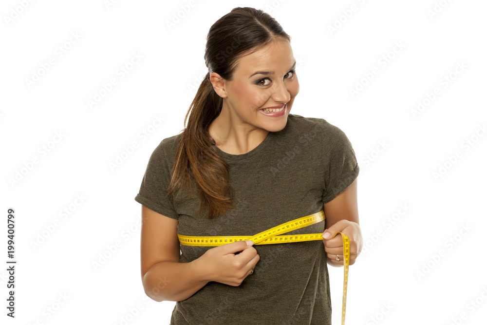 Happy young woman measuring her breasts on white background Happy young woman measuring her breasts on white background