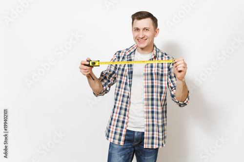Young smiling handsome man in casual clothes holding measure tape isolated on white background. Instruments, accessories, tools for renovation apartment room. Repair home concept. Advertising area.