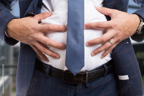 Male grabbing bloated abdomen as indigestion problem.