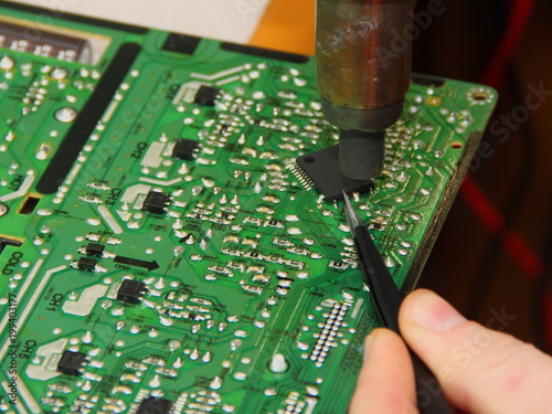 Soldering chips - hand with tweezers and heater fan sets the processor on the PCB