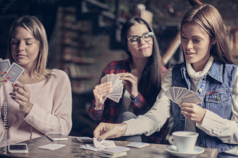 Three girls playing card in cafe. Three girls playing card in cafe.