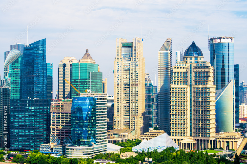 Fototapeta premium Aerial view of Shanghai's high density central business area. High rise office buildings and skyscrapers with glass surface. Urban roads with multiple lanes and green city park. Shanghai, China