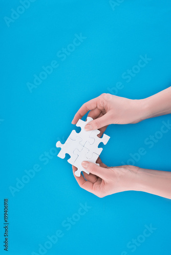 cropped image of businesswoman holding assembled puzzles isolated on blue, business concept