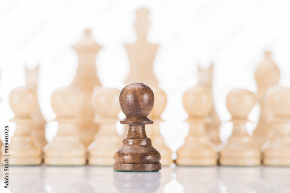 black chess pawn in front of white figures on white black chess pawn in front of white figures on white