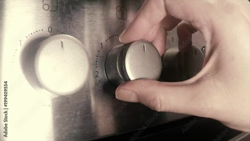 Hand turning knob to switch on stove plate Hand turning knob to switch on stove plate