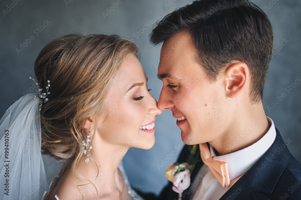 Naklejka premium Beautiful newlyweds gently embrace in the studio. Close-up portrait of a newly-married couple.