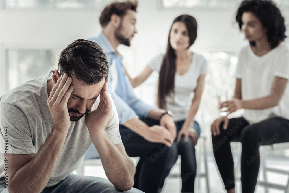 Stressed out. Nice serious upset man sitting on the chair and holding his head while being stressed out Stressed out. Nice serious upset man sitting on the chair and holding his head while being stressed out